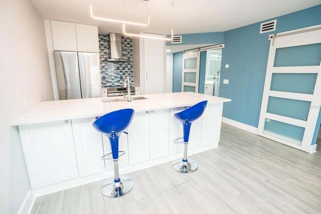 5712 Biscayne Ct Unit 201, New Port Richey, FL 34652 - kitchen featuring stainless steel fridge, wall chimney range hood, tasteful backsplash, a sink, and a peninsula