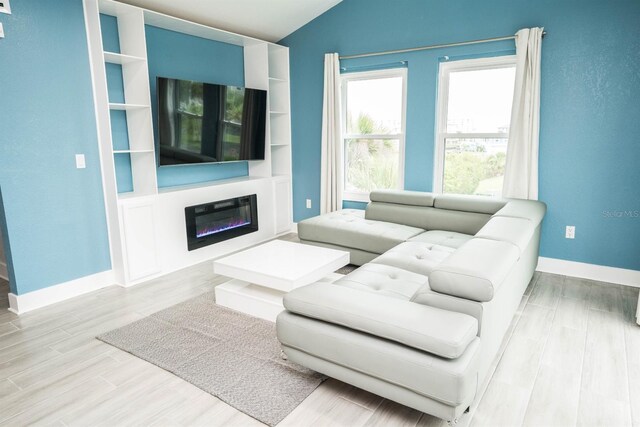 5712 Biscayne Ct Unit 201, New Port Richey, FL 34652 - living room featuring wood finished floors, baseboards, a glass covered fireplace, and lofted ceiling