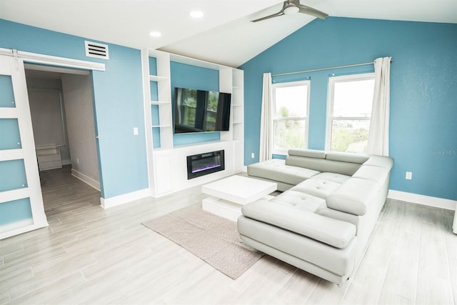 5712 Biscayne Ct Unit 201, New Port Richey, FL 34652 - living area featuring ceiling fan, light wood-type flooring, baseboards, a glass covered fireplace, and vaulted ceiling