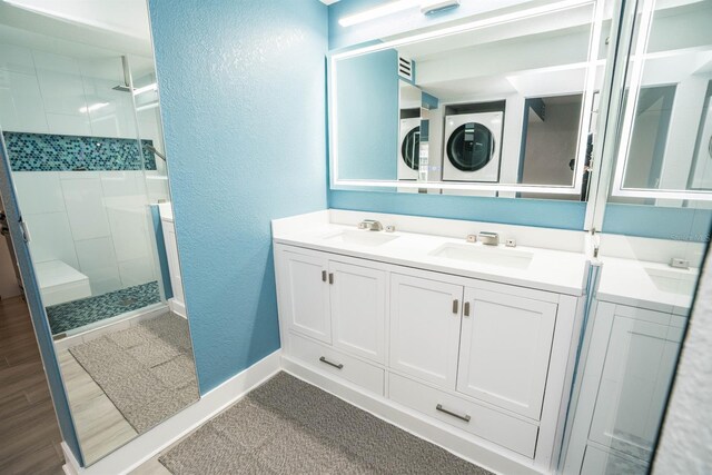 5712 Biscayne Ct Unit 201, New Port Richey, FL 34652 - full bathroom featuring estacked washer and dryer, a textured wall, a stall shower, double vanity, and baseboards