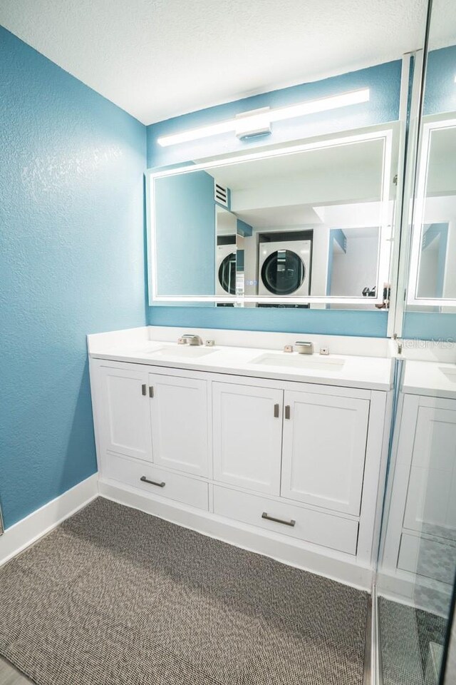 5712 Biscayne Ct Unit 201, New Port Richey, FL 34652 - bathroom with double vanity, a textured wall, baseboards, and stacked washer / dryer