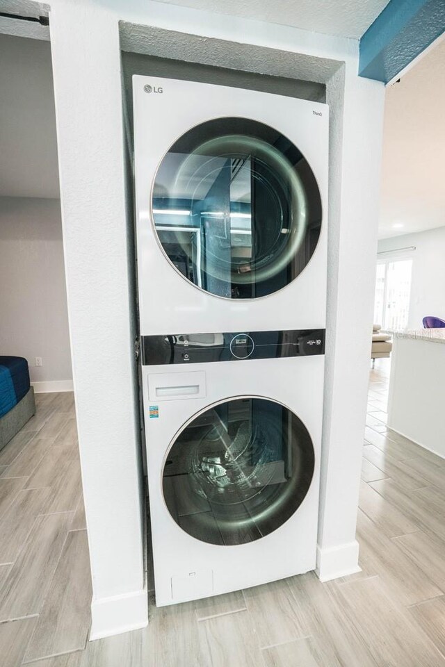 5712 Biscayne Ct Unit 201, New Port Richey, FL 34652 - washroom featuring stacked washer and clothes dryer, light wood-style floors, and baseboards