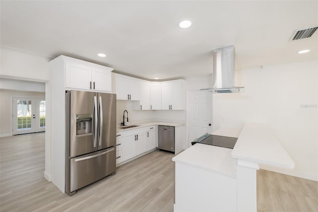 3947 Overlook Dr NE, Saint Petersburg, FL 33703 - kitchen with stainless steel appliances, island exhaust hood, a sink, a peninsula, and light wood-style flooring