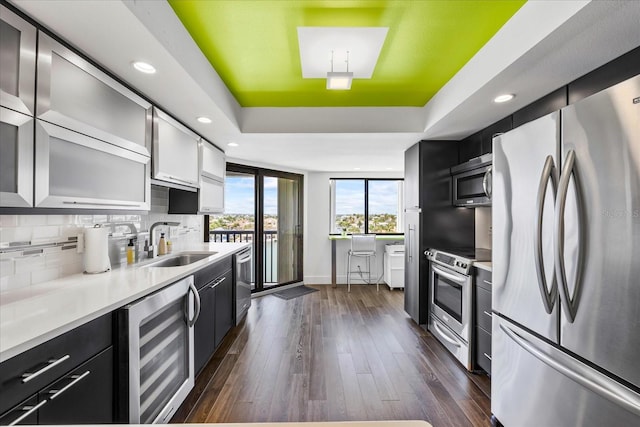 1651 Sand Key Estates Ct Unit 54, Clearwater Beach, FL 33767 - kitchen with appliances with stainless steel finishes, wine cooler, a sink, a raised ceiling, and dark cabinets