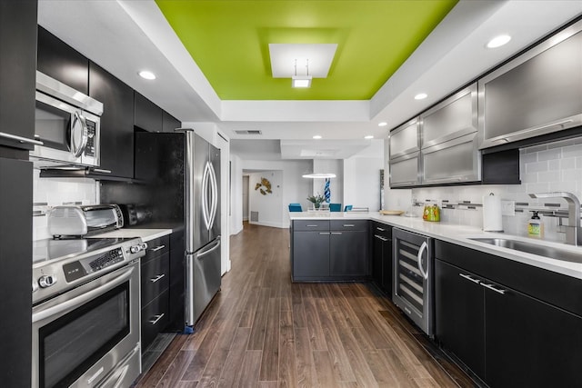 1651 Sand Key Estates Ct Unit 54, Clearwater Beach, FL 33767 - kitchen featuring stainless steel appliances, beverage cooler, dark cabinets, a sink, and a peninsula