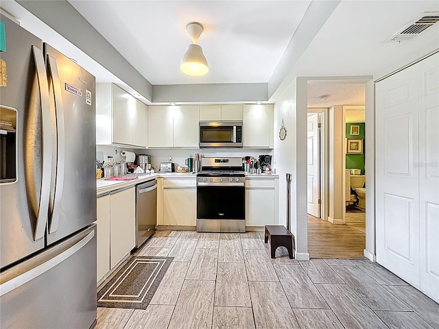5920 80th St N Unit 406, Saint Petersburg, FL 33709 - kitchen featuring appliances with stainless steel finishes, light countertops, wood finish floors, and white cabinets