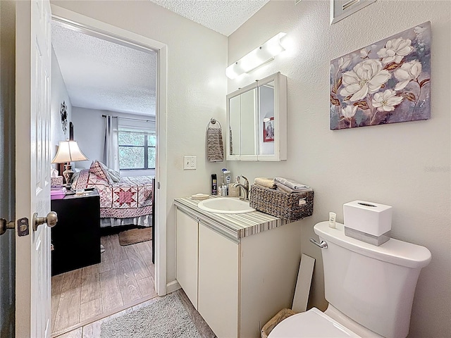 5920 80th St N Unit 406, Saint Petersburg, FL 33709 - ensuite bathroom with vanity, toilet, a textured ceiling, and wood finished floors