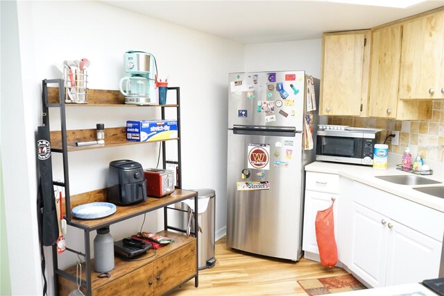 413 Lake Point Ct Unit 4B, Sun City Center, FL 33573 - kitchen with appliances with stainless steel finishes, light wood-style floors, light countertops, decorative backsplash, and a sink