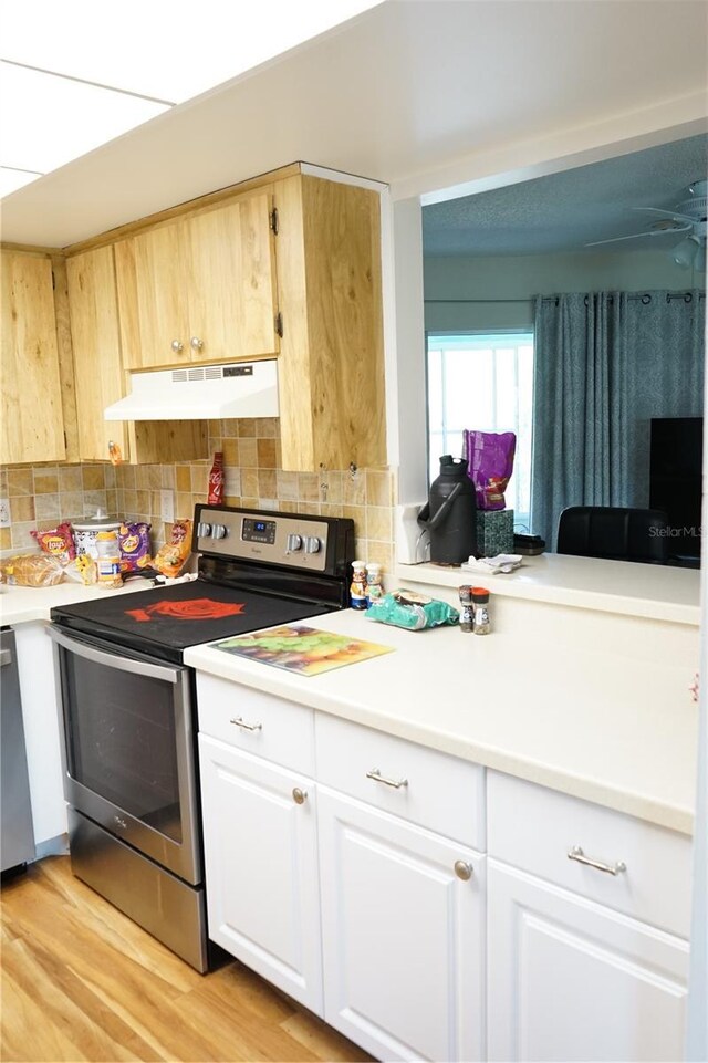 413 Lake Point Ct Unit 4B, Sun City Center, FL 33573 - kitchen featuring stainless steel range with electric cooktop, under cabinet range hood, decorative backsplash, light countertops, and light wood-style flooring