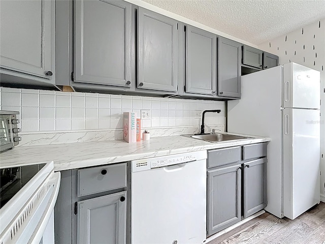 147 114th Ave NE Unit 147, Saint Petersburg, FL 33716 - kitchen with gray cabinetry, white appliances, a sink, light wood-style floors, and backsplash