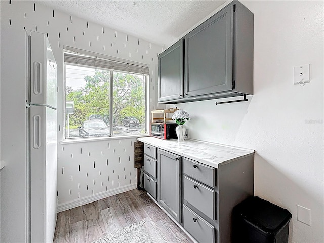 147 114th Ave NE Unit 147, Saint Petersburg, FL 33716 - kitchen featuring gray cabinets, light wood-style floors, a textured ceiling, light stone countertops, and freestanding refrigerator