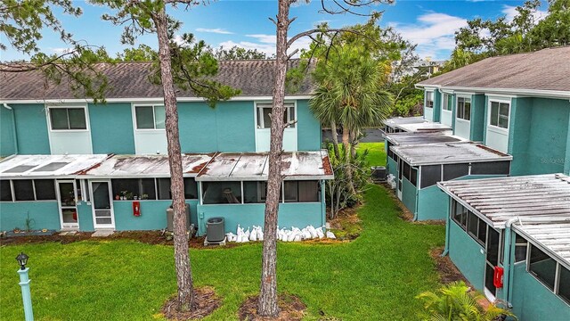 147 114th Ave NE Unit 147, Saint Petersburg, FL 33716 - rear view of house featuring a sunroom, a yard, stucco siding, and central AC