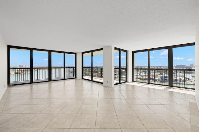 9425 Blind Pass Rd Unit 1008, St Pete Beach, FL 33706 - spare room with floor to ceiling windows, light tile patterned floors, and a water view