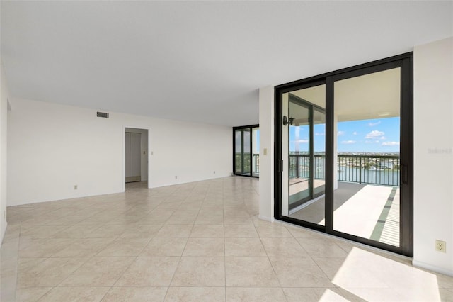 9425 Blind Pass Rd Unit 1008, St Pete Beach, FL 33706 - empty room featuring floor to ceiling windows, light tile patterned floors, and a water view