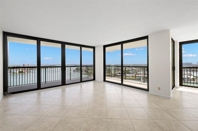 9425 Blind Pass Rd Unit 1008, St Pete Beach, FL 33706 - tiled spare room featuring floor to ceiling windows, a water view, plenty of natural light, and baseboards