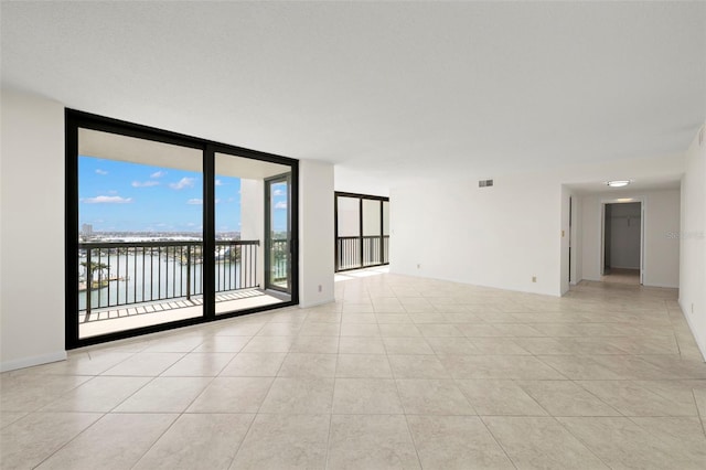 9425 Blind Pass Rd Unit 1008, St Pete Beach, FL 33706 - empty room featuring expansive windows, a water view, and light tile patterned floors