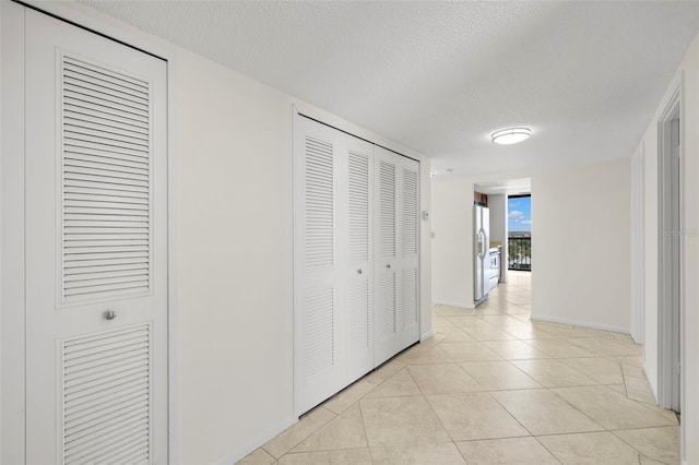 9425 Blind Pass Rd Unit 1008, St Pete Beach, FL 33706 - hallway featuring light tile patterned floors, a textured ceiling, and baseboards