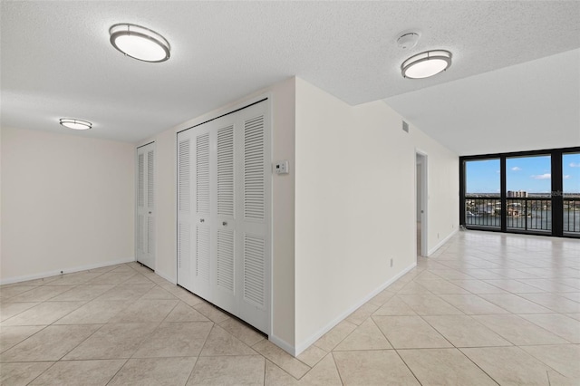9425 Blind Pass Rd Unit 1008, St Pete Beach, FL 33706 - hall featuring light tile patterned floors, a textured ceiling, and baseboards