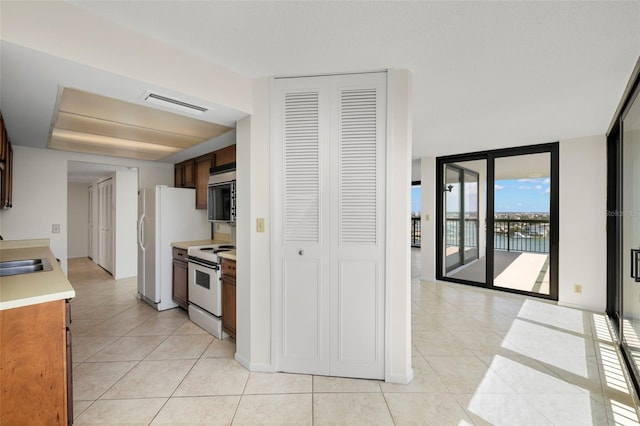 9425 Blind Pass Rd Unit 1008, St Pete Beach, FL 33706 - kitchen featuring white appliances, light tile patterned floors, a sink, and light countertops