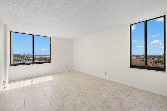 9425 Blind Pass Rd Unit 1008, St Pete Beach, FL 33706 - spare room with tile patterned flooring, baseboards, a textured ceiling, and expansive windows
