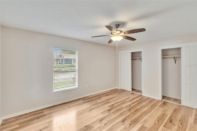 125 Picardy Villa Cir Unit 100, Brandon, FL 33510 - unfurnished bedroom with two closets, light wood-type flooring, baseboards, ceiling fan, and a textured ceiling