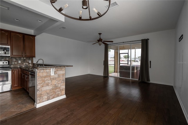 6940 47th Way N, Pinellas Park, FL 33781 - kitchen featuring appliances with stainless steel finishes, open floor plan, a peninsula, tasteful backsplash, and dark wood-type flooring