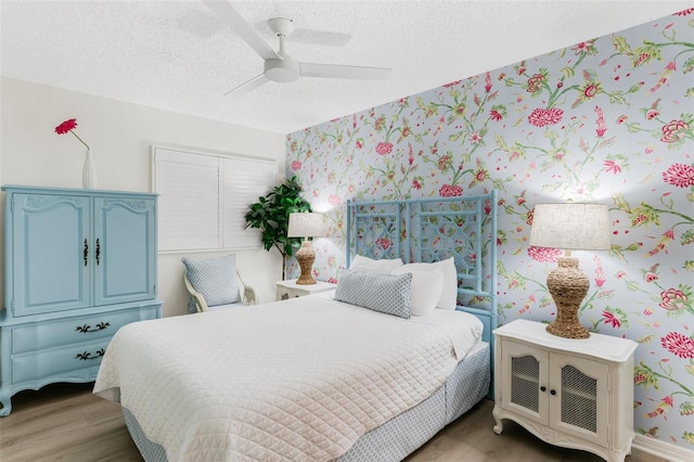 17334 Gulf Blvd Unit 203, North Redington Beach, FL 33708 - bedroom featuring a textured ceiling, light wood-style flooring, ceiling fan, and wallpapered walls