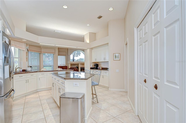 4304 Place Le Manes, Lutz, FL 33558 - kitchen with stainless steel refrigerator with ice dispenser, a breakfast bar, light tile patterned floors, white cabinetry, and recessed lighting