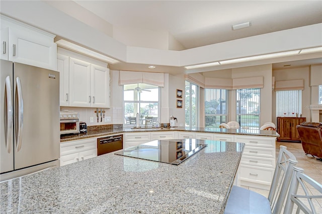 4304 Place Le Manes, Lutz, FL 33558 - kitchen featuring freestanding refrigerator, black electric cooktop, dishwashing machine, a peninsula, and light stone countertops