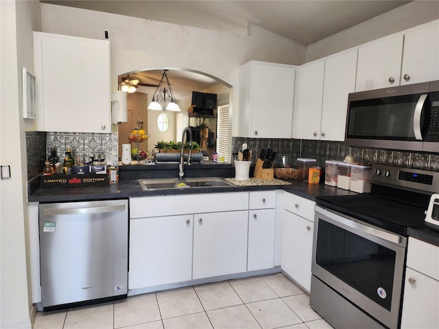 8313 Arabian Dunes Pl, Riverview, FL 33578 - kitchen featuring stainless steel appliances, dark countertops, decorative backsplash, and white cabinetry