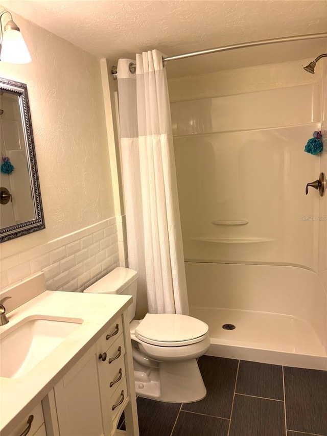 4020 55th St N Unit 1106, Kenneth City, FL 33709 - bathroom featuring a textured ceiling, toilet, a textured wall, tile walls, and vanity