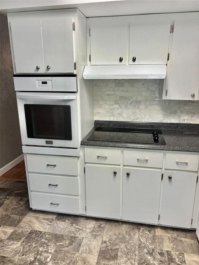 4020 55th St N Unit 1106, Kenneth City, FL 33709 - kitchen featuring white oven, black electric stovetop, white cabinets, under cabinet range hood, and backsplash