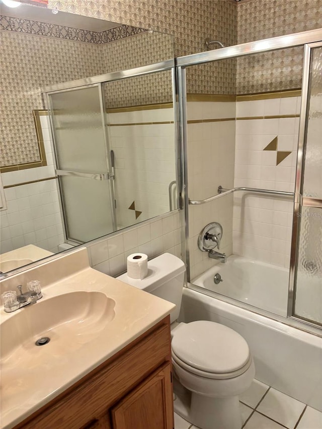4020 55th St N Unit 1106, Kenneth City, FL 33709 - bathroom featuring tile walls, bath / shower combo with glass door, vanity, toilet, and tile patterned flooring