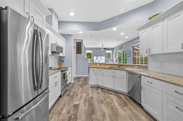 4505 Anaconda Dr, New Port Richey, FL 34655 - kitchen featuring stainless steel appliances, a sink, light wood-type flooring, tasteful backsplash, and a peninsula