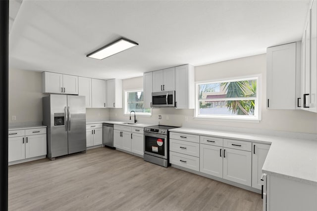 837 E Edgewood Dr, Lakeland, FL 33803 - kitchen with appliances with stainless steel finishes, a sink, light wood-type flooring, light countertops, and white cabinetry