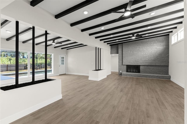 837 E Edgewood Dr, Lakeland, FL 33803 - unfurnished living room featuring ceiling fan, baseboards, beam ceiling, a stone fireplace, and wood finished floors