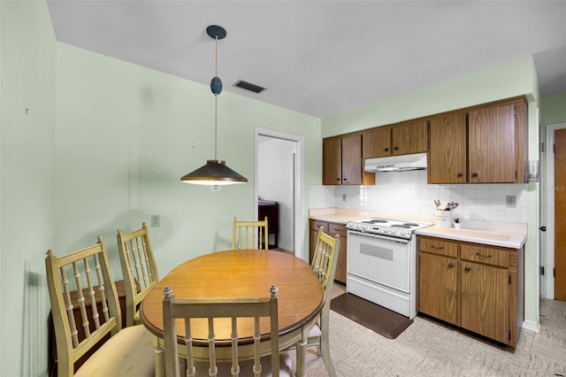 321 Belle View Ave, Temple Terrace, FL 33617 - kitchen featuring white range with electric cooktop, under cabinet range hood, tasteful backsplash, light countertops, and brown cabinets