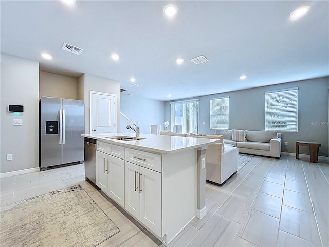 32451 Limitless Pl, Wesley Chapel, FL 33545 - kitchen featuring appliances with stainless steel finishes, a sink, white cabinetry, a kitchen island with sink, and light countertops