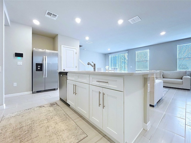 32451 Limitless Pl, Wesley Chapel, FL 33545 - kitchen featuring stainless steel appliances, white cabinets, a kitchen island with sink, open floor plan, and light countertops
