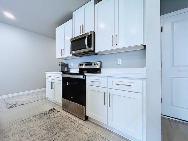 32451 Limitless Pl, Wesley Chapel, FL 33545 - kitchen with appliances with stainless steel finishes, white cabinets, light countertops, baseboards, and wood tiled floors