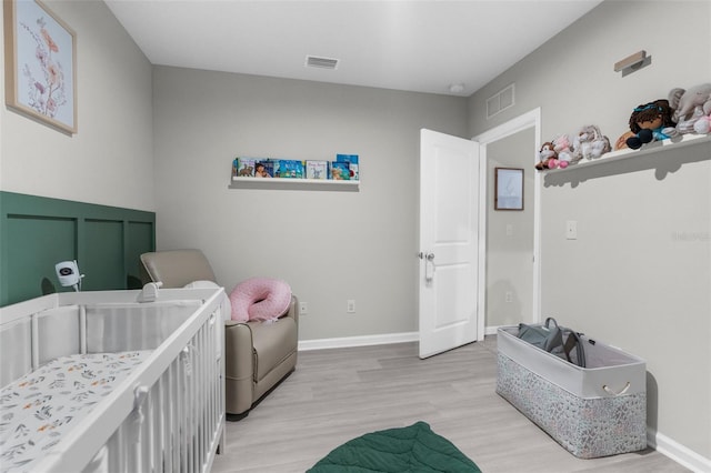 14532 Whitewater Way, Brooksville, FL 34604 - bedroom featuring light wood-style flooring, a crib, and baseboards