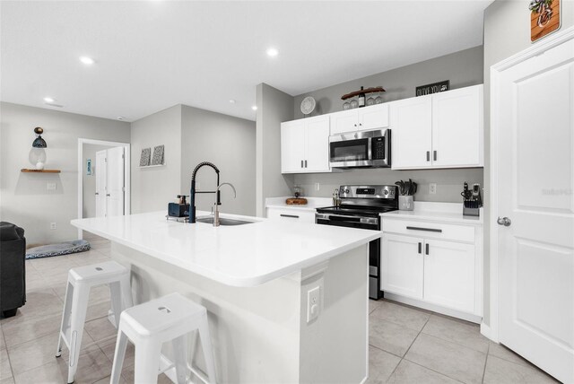 14532 Whitewater Way, Brooksville, FL 34604 - kitchen featuring appliances with stainless steel finishes, a sink, light tile patterned floors, a center island with sink, and a kitchen bar