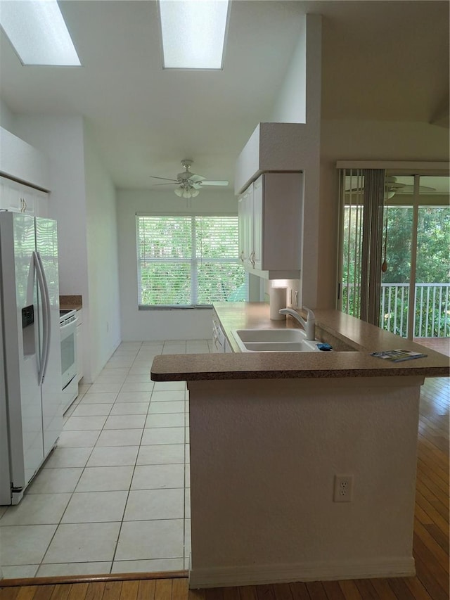 1605 Send Way, Lutz, FL 33549 - kitchen featuring white appliances, a peninsula, a skylight, white cabinets, and light wood-style flooring