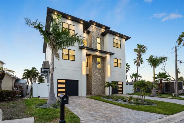 820 Bay Point Dr, Madeira Beach, FL 33708 - contemporary home featuring stucco siding, decorative driveway, stone siding, and a garage