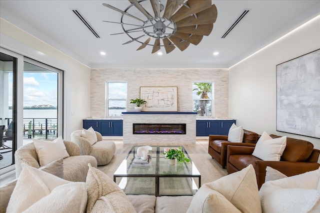 820 Bay Point Dr, Madeira Beach, FL 33708 - living room featuring a glass covered fireplace, light wood-type flooring, ceiling fan, recessed lighting, and a water view