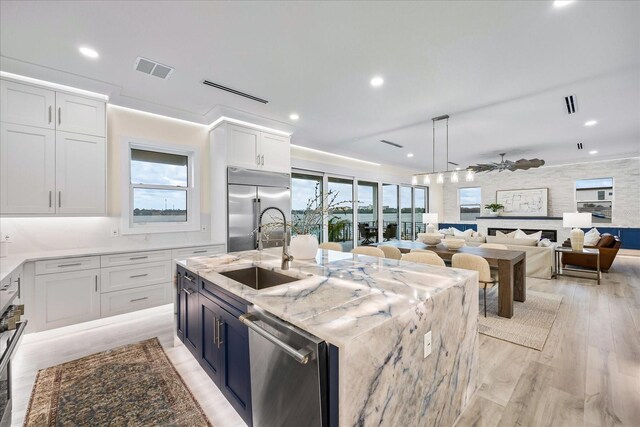 820 Bay Point Dr, Madeira Beach, FL 33708 - kitchen with appliances with stainless steel finishes, a sink, white cabinets, light wood finished floors, and plenty of natural light