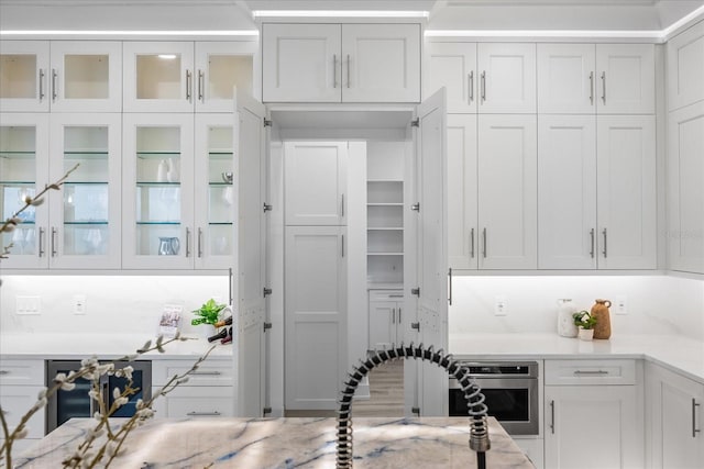 820 Bay Point Dr, Madeira Beach, FL 33708 - kitchen featuring white cabinetry, glass insert cabinets, light stone countertops, and oven