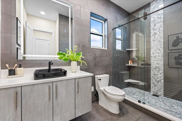 820 Bay Point Dr, Madeira Beach, FL 33708 - bathroom featuring a stall shower, toilet, vanity, tile walls, and tile patterned floors
