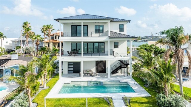 820 Bay Point Dr, Madeira Beach, FL 33708 - back of house with a standing seam roof, stairway, a balcony, stucco siding, and metal roof