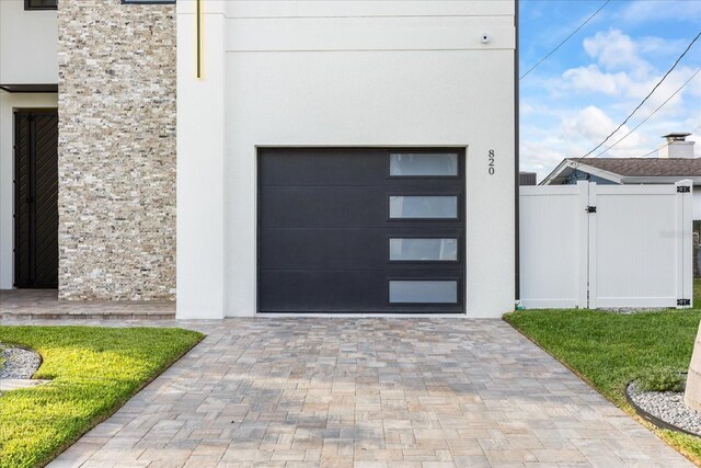 820 Bay Point Dr, Madeira Beach, FL 33708 - view of exterior entry with a garage, decorative driveway, stucco siding, and a gate
